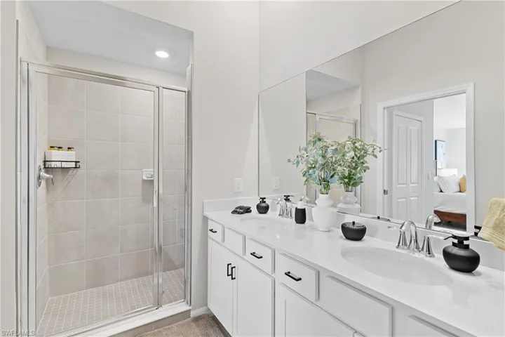 Ensuite bathroom featuring a shower stall, double vanity, and recessed lighting