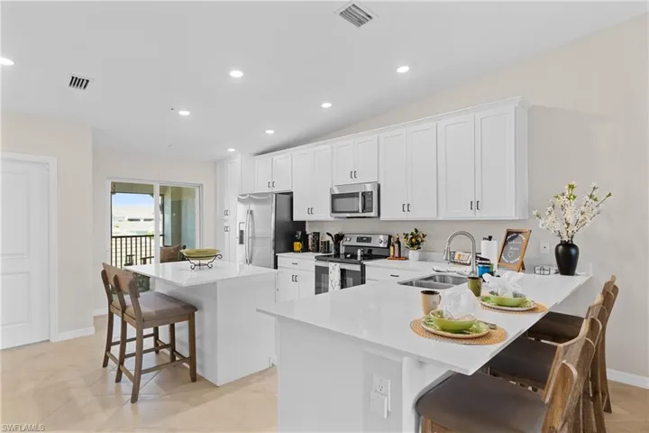 Kitchen with a breakfast bar area, stainless steel appliances, recessed lighting, a kitchen island, and white cabinetry