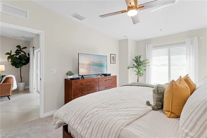 Bedroom with light carpet, ceiling fan, and light tile patterned floors