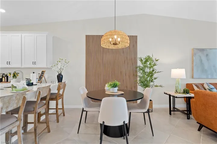 Dining space featuring a chandelier, vaulted ceiling, and light tile patterned floors