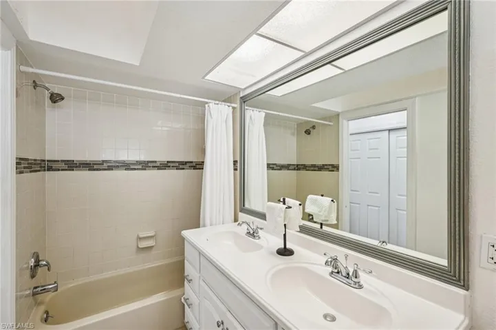 Full bath featuring shower / bathtub combination with curtain and double vanity