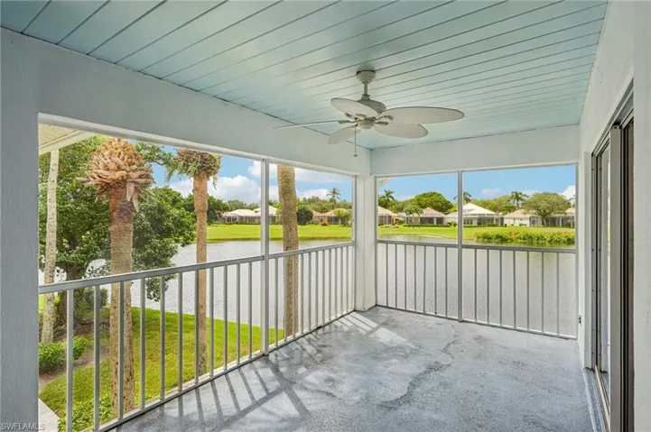 Unfurnished sunroom with a ceiling fan, a water view, and a residential view