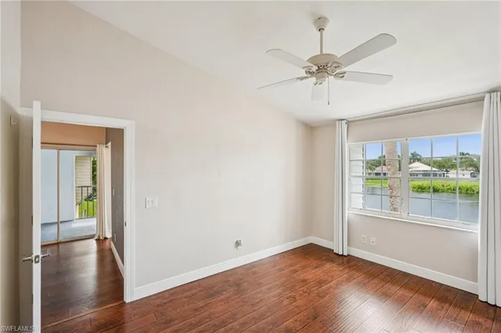 Empty room with healthy amount of natural light, dark wood-type flooring, ceiling fan, and lofted ceiling