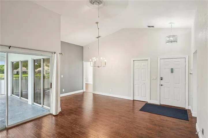Foyer featuring high vaulted ceiling, a chandelier, dark wood-type flooring, and a water view