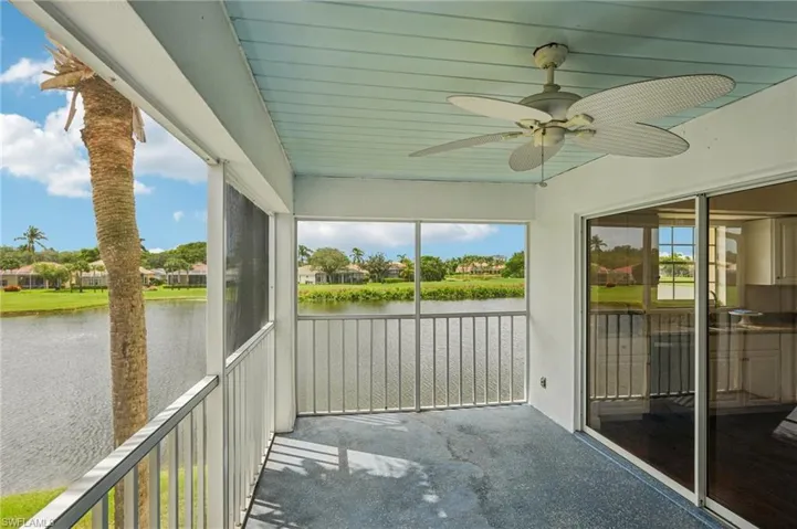 Unfurnished sunroom featuring a ceiling fan, a residential view, and a water view