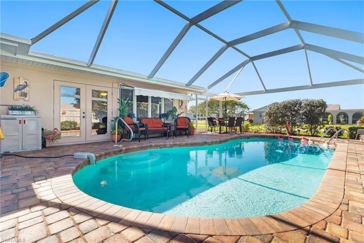View of screened lanai with swimming pool, pavers and French doors, and outdoor living space, a patio area