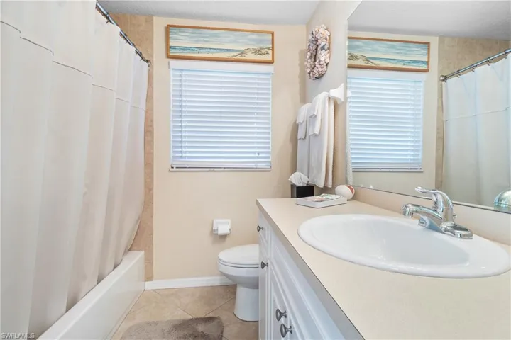 Guest bathroom with tile patterned floors, vanity, toilet, and a wealth of natural light