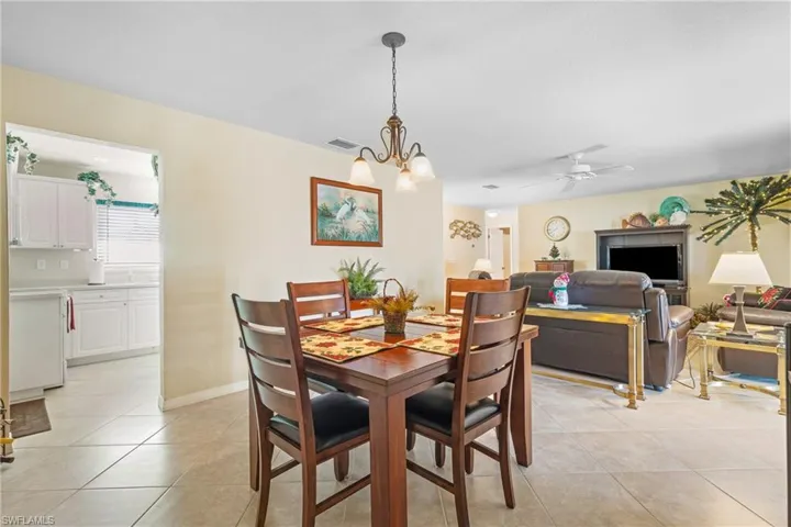 Dining space with ceiling fan with notable chandelier and light tile patterned floors