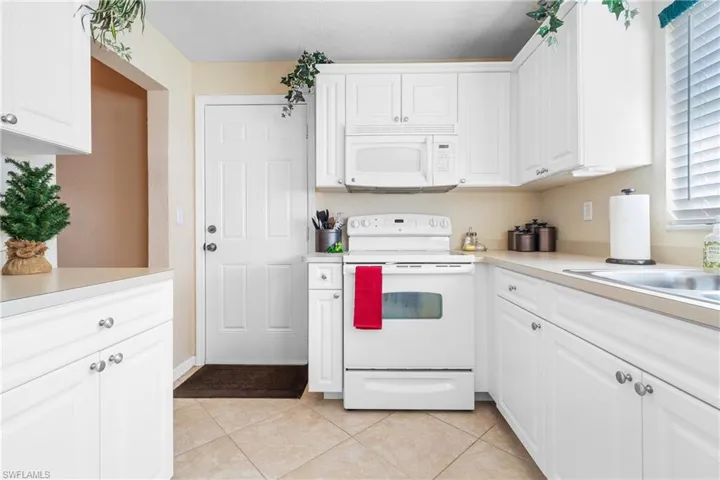 Kitchen featuring light tile patterned floors, white cabinets, and white appliances