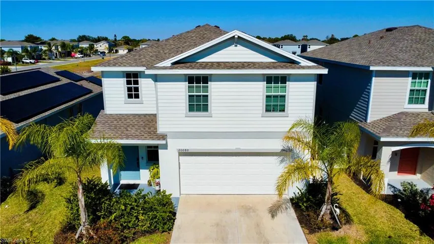 View of front of home with roof with shingles, an attached garage, a residential view, driveway, and stucco siding