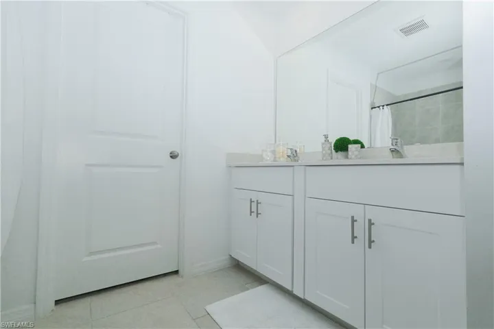 Full bathroom with double vanity, light tile patterned floors, and a tile shower