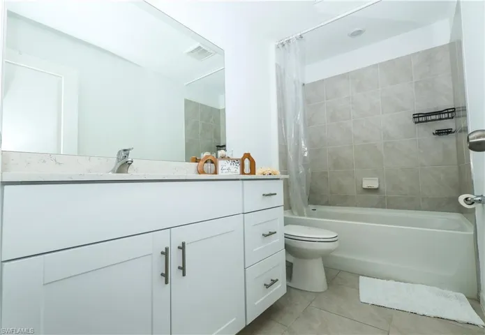 Bathroom featuring shower / bath combo with shower curtain, vanity, and light tile patterned floors