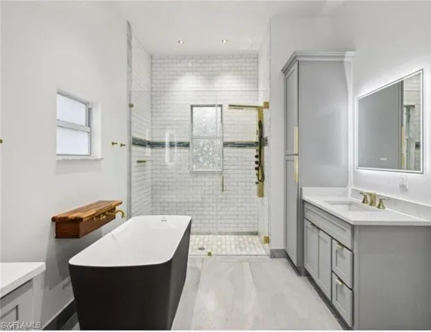 Full bath featuring a freestanding tub, vanity, and a stall shower