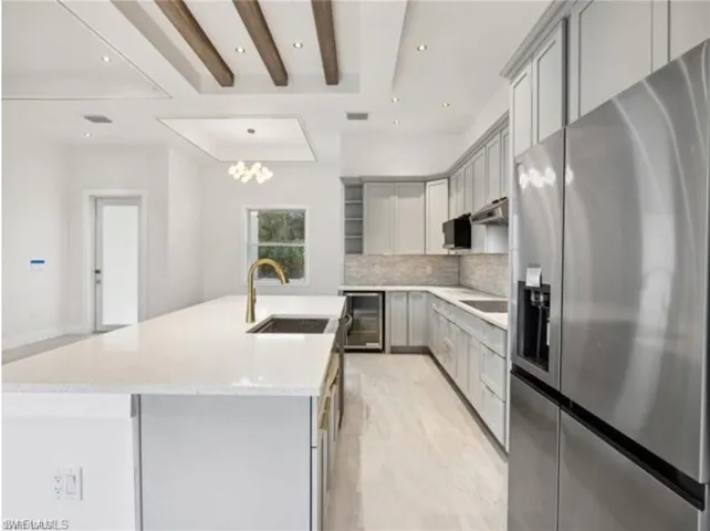 Kitchen with gray cabinetry, a sink, wine cooler, and stainless steel fridge