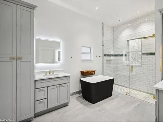 Bathroom featuring a soaking tub, vanity, and a stall shower