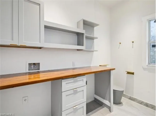 Kitchen with open shelves, butcher block counters, built in study area, and baseboards