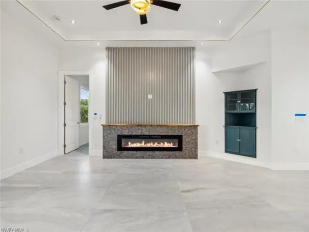 Unfurnished living room with baseboards, a ceiling fan, a glass covered fireplace, and recessed lighting