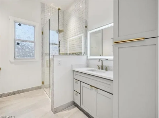 Bathroom with baseboards, vanity, and a stall shower