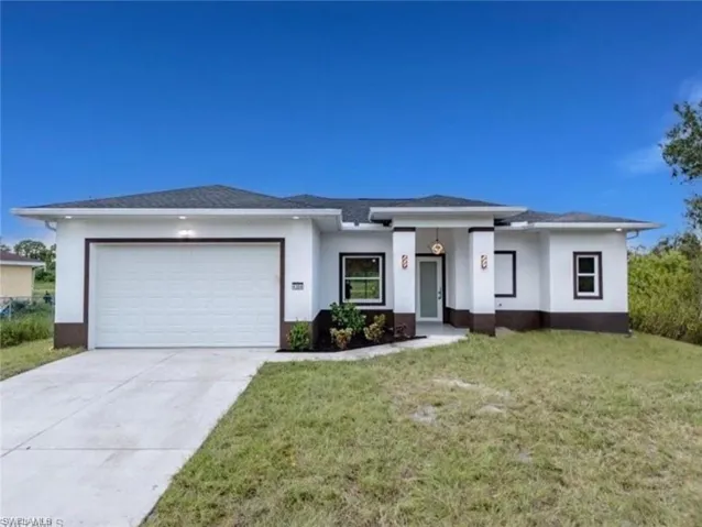 Prairie-style house with an attached garage, concrete driveway, a front yard, and stucco siding