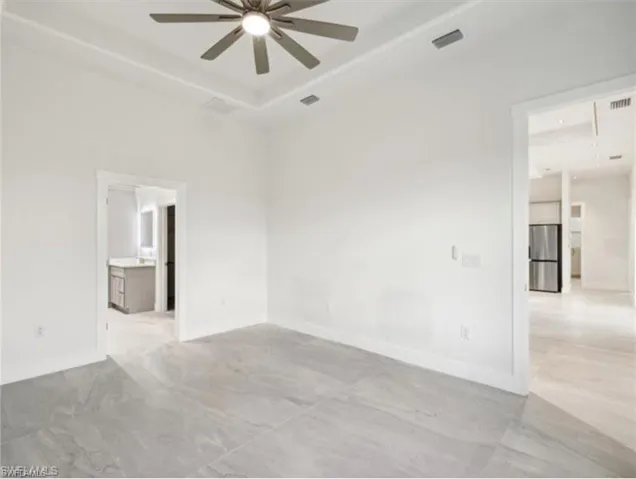 Empty room featuring baseboards, a ceiling fan, visible vents, and a raised ceiling