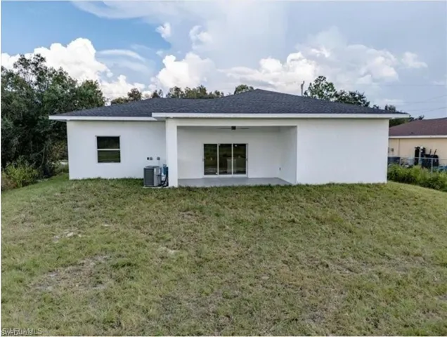 Rear view of house with stucco siding, central air condition unit, a yard, and a ceiling fan