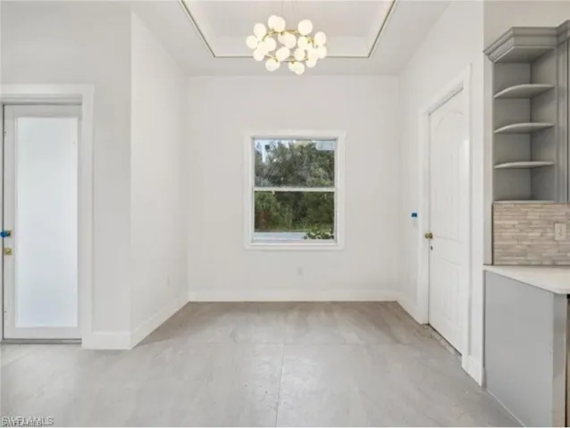 Unfurnished dining area with built in shelves, baseboards, and a notable chandelier