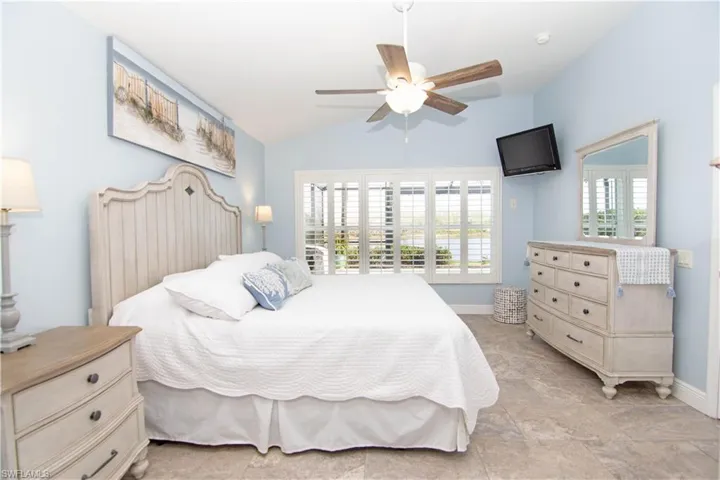 Primary bedroom suite features a vaulted ceiling, tile floors and plantation blinds.