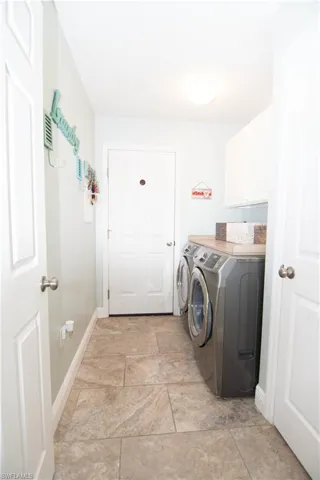Washroom featuring independent washer and dryer, cabinet space, and baseboards