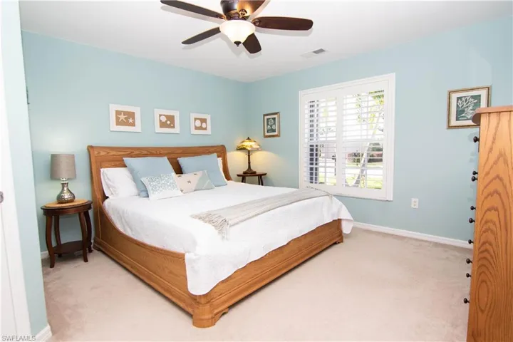 Carpeted bedroom with baseboards, visible vents, and a ceiling fan