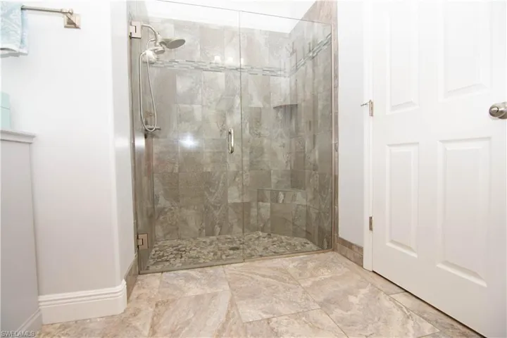 Custom oversized shower features beautiful tile work and glass doors.