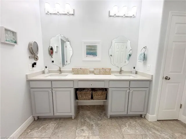 Fully remodeled primary bath features a dual vanity with stylish lighting and tile flooring.