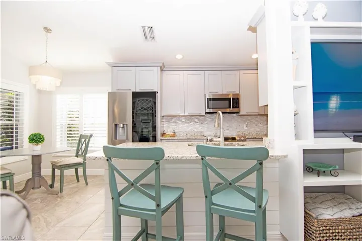 Gorgeous remodelled kitchen features tiled backsplash, light stone countertops, stainless steel appliances and beautiful cabinets with crown molding.