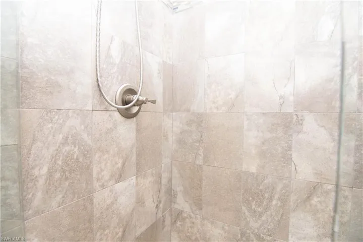 Closeup view of the tiled shower and brushed stainless fixtures.