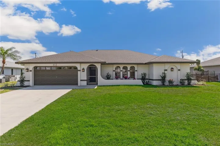 Ranch-style home with a garage, stucco siding, driveway, and a front yard