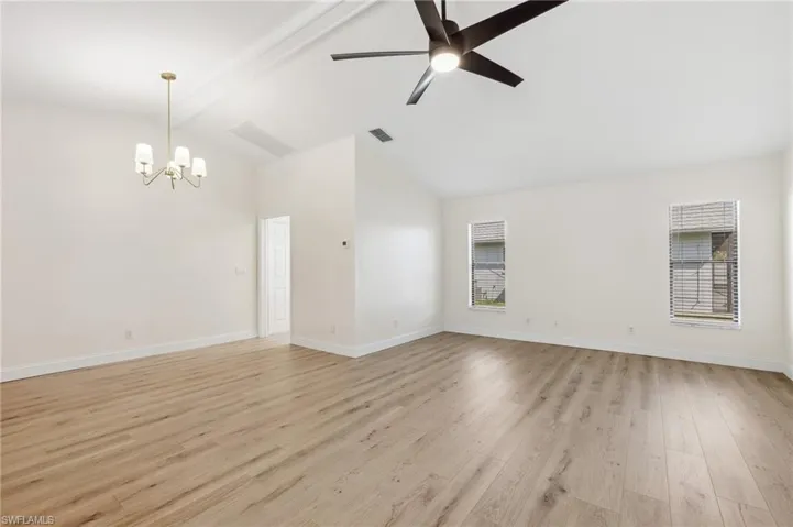 Empty room with ceiling fan with notable chandelier, visible vents, baseboards, beam ceiling, and light wood finished floors
