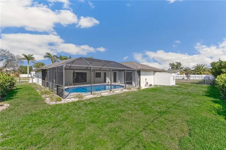 Back of property featuring a fenced in pool, a lanai, a fenced backyard, and a yard