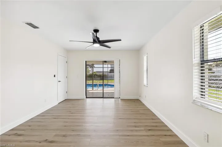 Empty room featuring light wood-style floors, visible vents, baseboards, and a ceiling fan