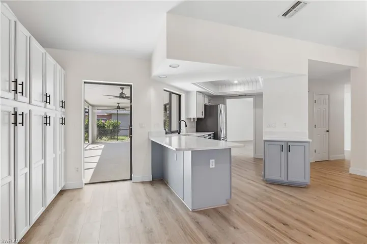Kitchen with visible vents, white cabinets, a breakfast bar area, a peninsula, and light countertops