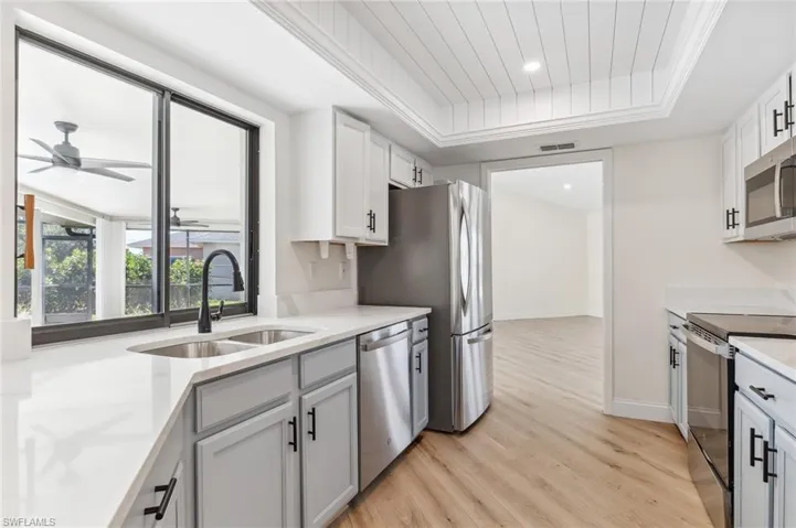 Kitchen featuring a tray ceiling, light countertops, visible vents, appliances with stainless steel finishes, and a sink