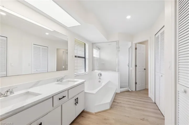 Full bathroom with a stall shower, a closet, a sink, and wood finished floors