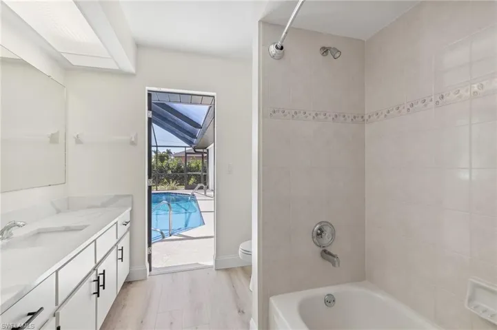 Full bath with bathtub / shower combination, toilet, wood finished floors, vanity, and baseboards