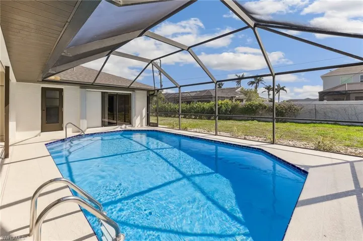 Pool featuring a lanai, a patio area, a lawn, and fence