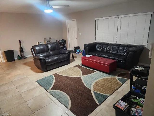 Living area featuring light tile patterned floors and ceiling fan