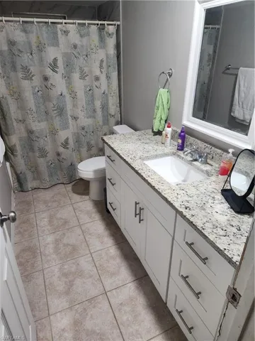 Full bathroom featuring vanity, a shower with shower curtain, and light tile patterned flooring