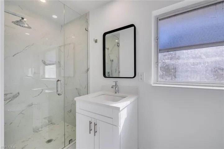 Bathroom featuring plenty of natural light, vanity, a marble finish shower, and recessed lighting