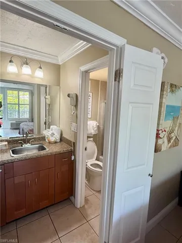 Vanity area featuring a wood-finish cabinet with panel doors, an integrated sink, and a speckled countertop