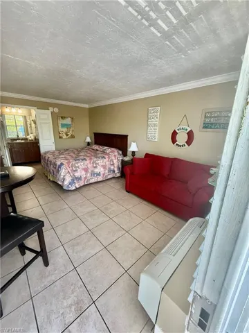 Spacious room featuring neutral-toned walls, crown molding, and large-format tile flooring