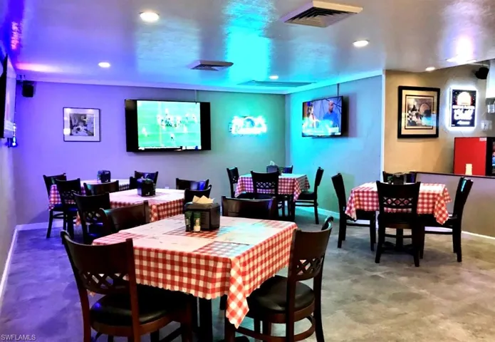 Spacious commercial interior featuring multiple wall-mounted screens, recessed lighting, and durable flooring
