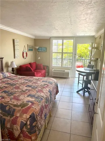 Open-plan room featuring tile flooring, crown molding, and a wall-mounted air conditioning unit