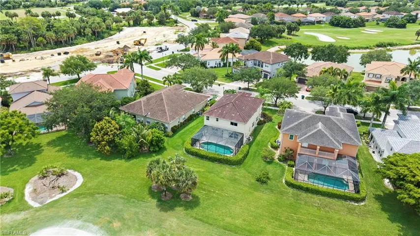Aerial view showcasing a residential property with a screened swimming pool, surrounded by manicured landscaping and mature trees